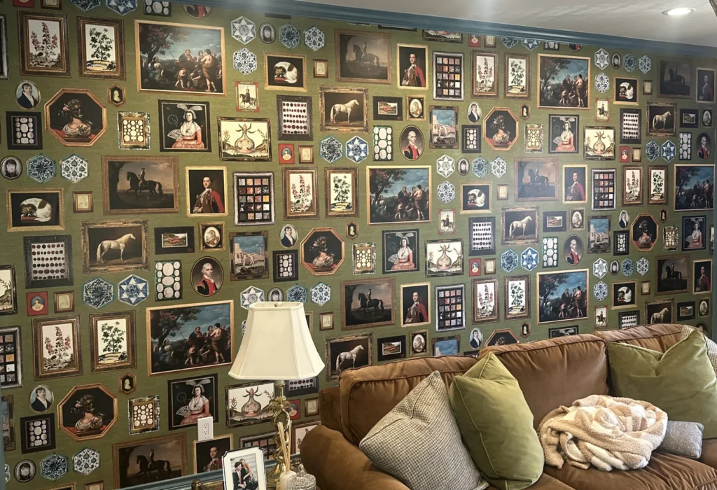 Living room accent wall featuring green wallpaper printed with an intricate gallery of framed classic portraits and art.