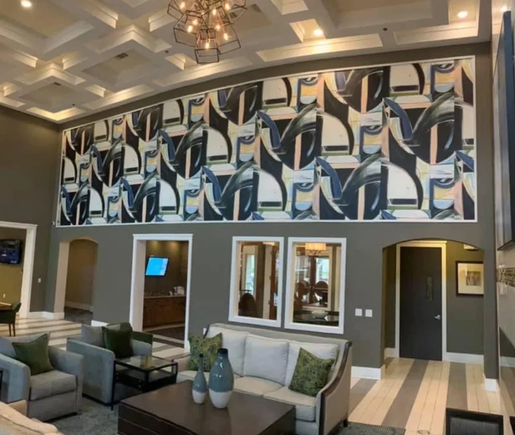 Large abstract wallcovering mural displayed above doorways in a spacious modern lobby with coffered ceilings and lounge seating.