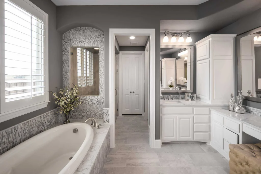 Spacious bathroom with dark grey painted walls, white cabinetry, a built-in soaking tub, and tile finishes.