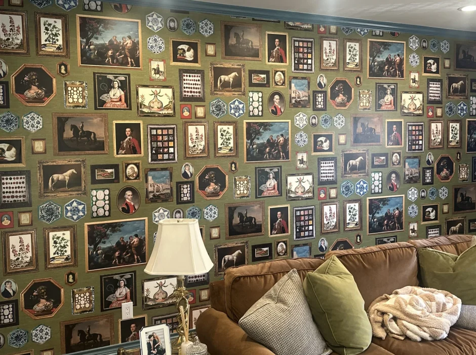 Living room accent wall featuring green wallpaper printed with an intricate gallery of framed classic portraits and art.