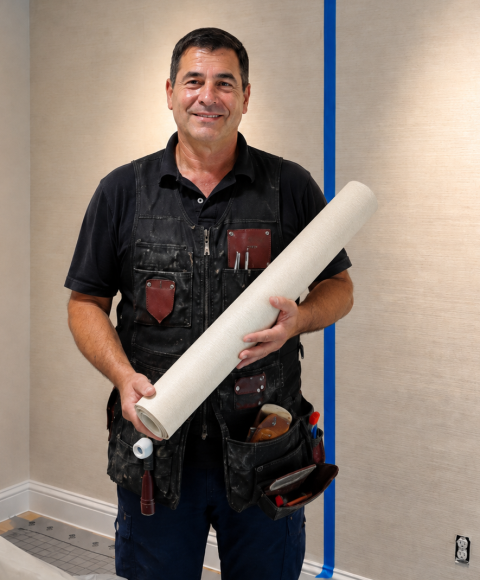 Joe James holding a roll of wallpaper on a job site