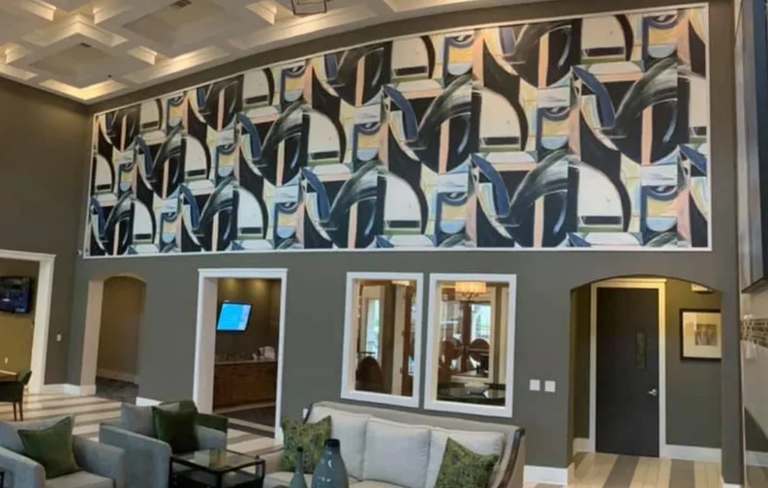 Large abstract wallcovering mural displayed above doorways in a spacious modern lobby with coffered ceilings and lounge seating.